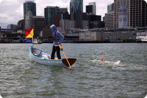 Dolphin Club swimmer alongside a handmade wooden support boat in SF